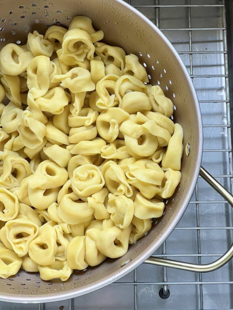 A colander filled with cooked fresh tortellini.