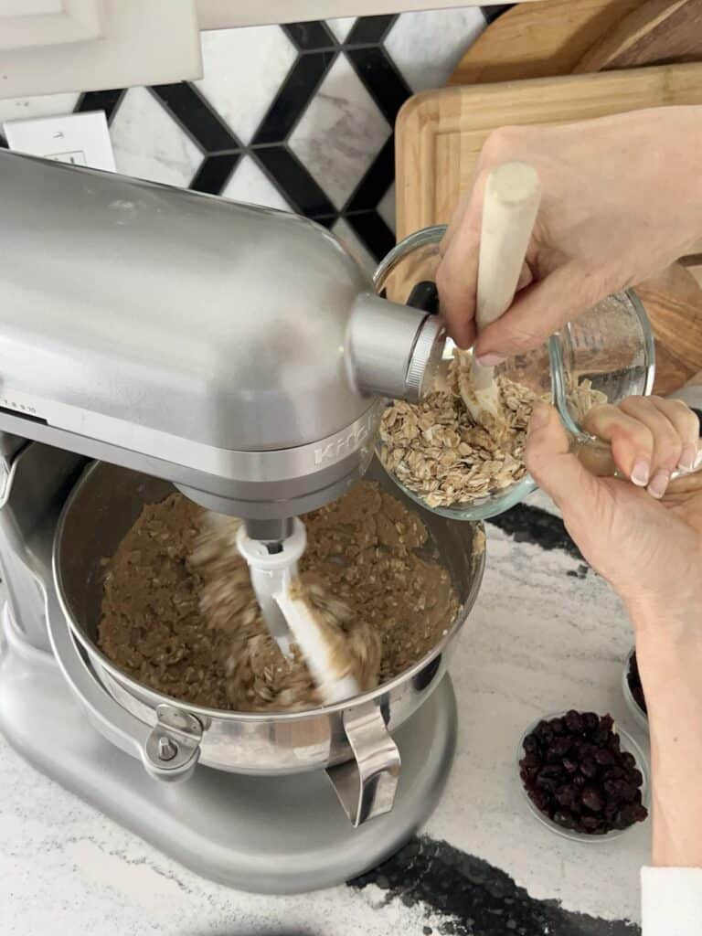 Pouring oats into a bowl for chewy oatmeal raisin cookies recipe  that have a bakery style flavor.