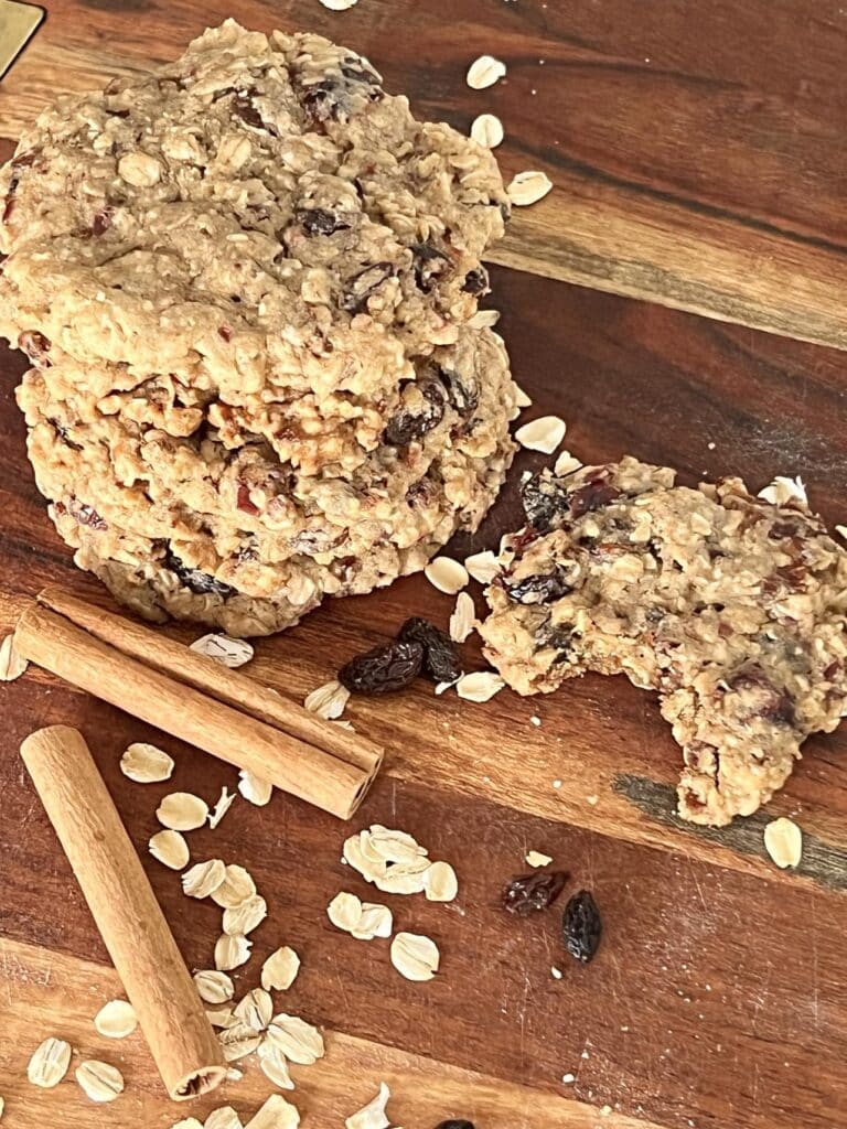 A stack of chewy oatmeal raisin bakery style cookies with a bite taken from one recipe cookie.