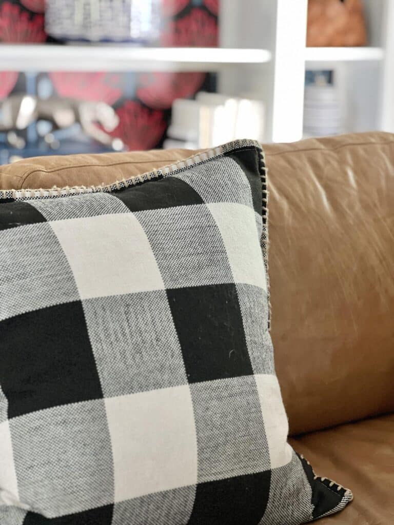 A clean black and cream buffalo check throw pillow on a sofa.