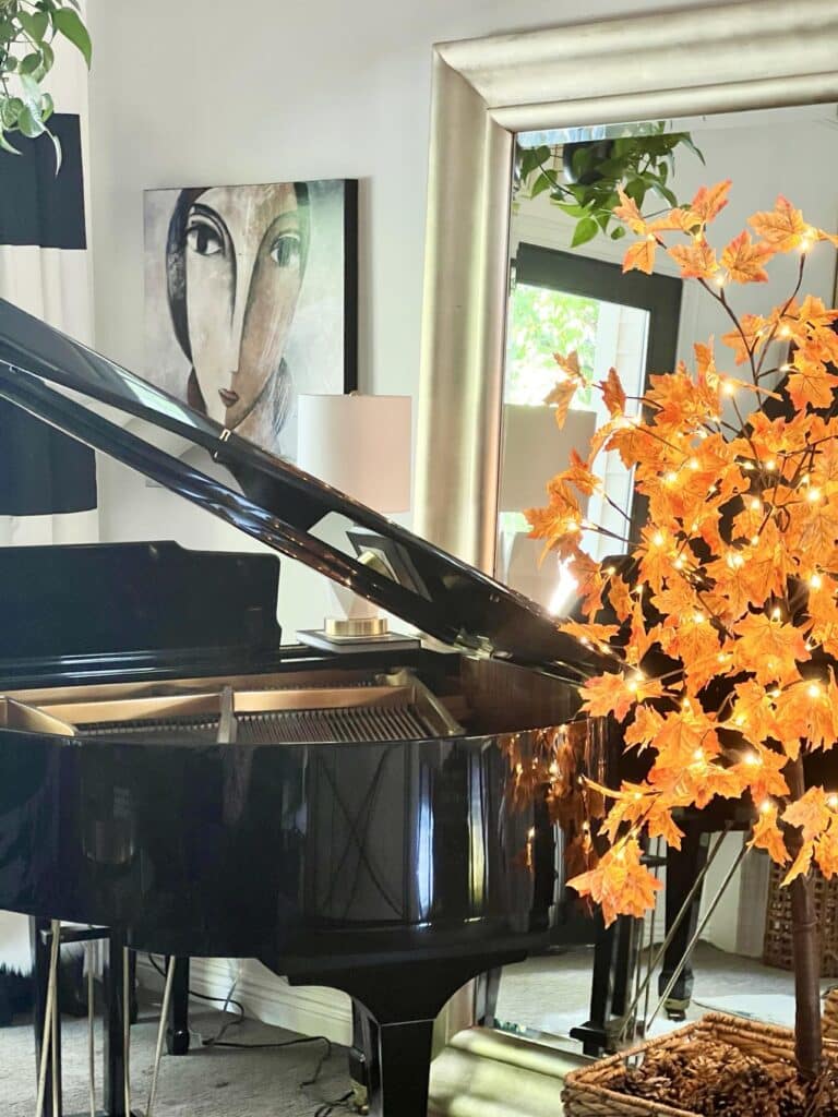 Faux maple tree beside a piano.