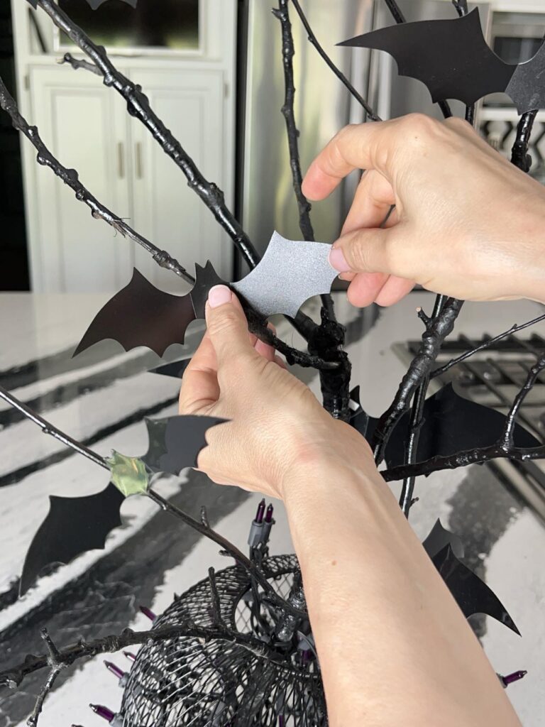 Holding diy black bats on branches while the glue dries.