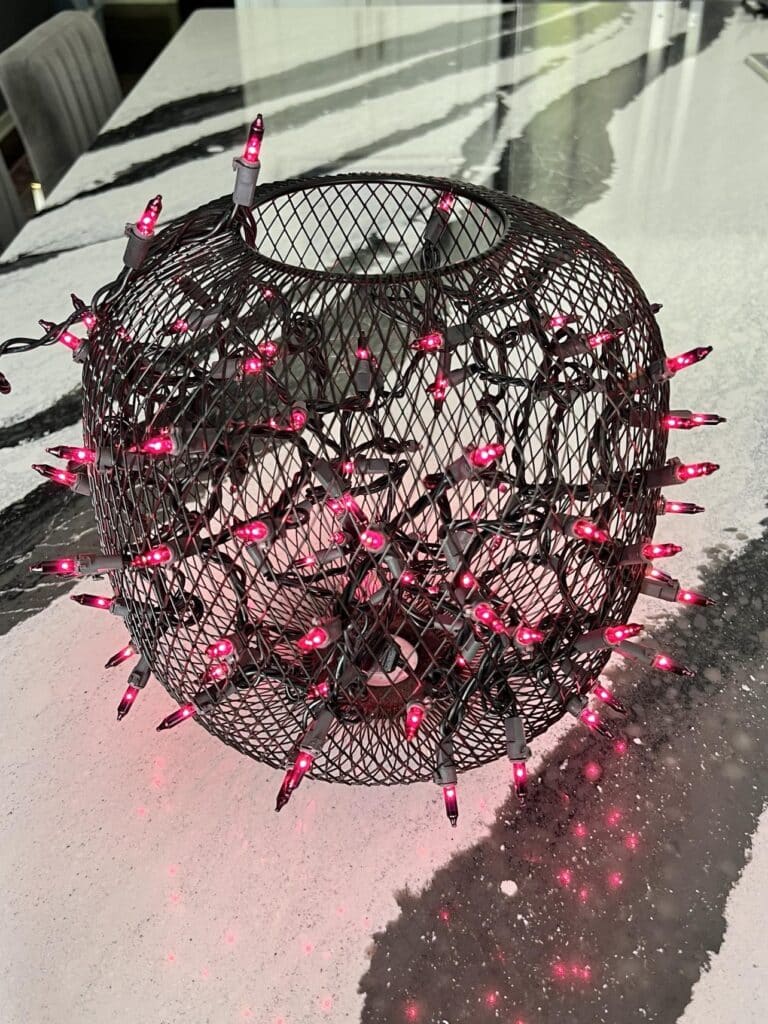 Illuminated purple string lights in a black mesh vase for a diy bat branches centerpiece.