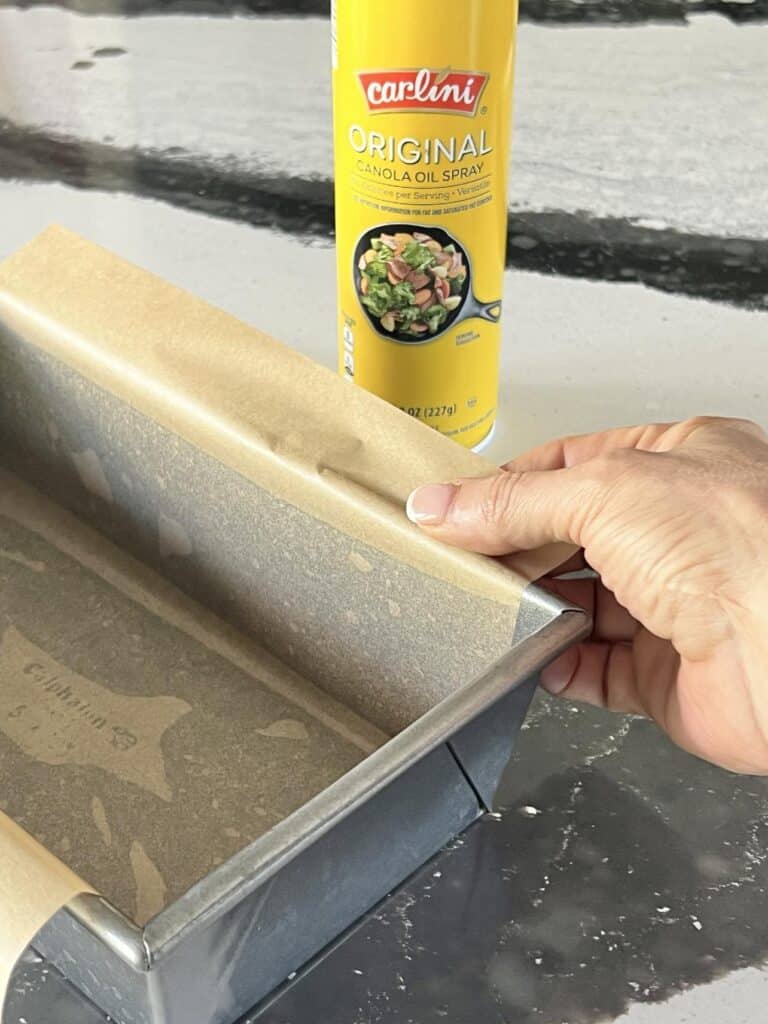 Lining a loaf pan with parchment paper.