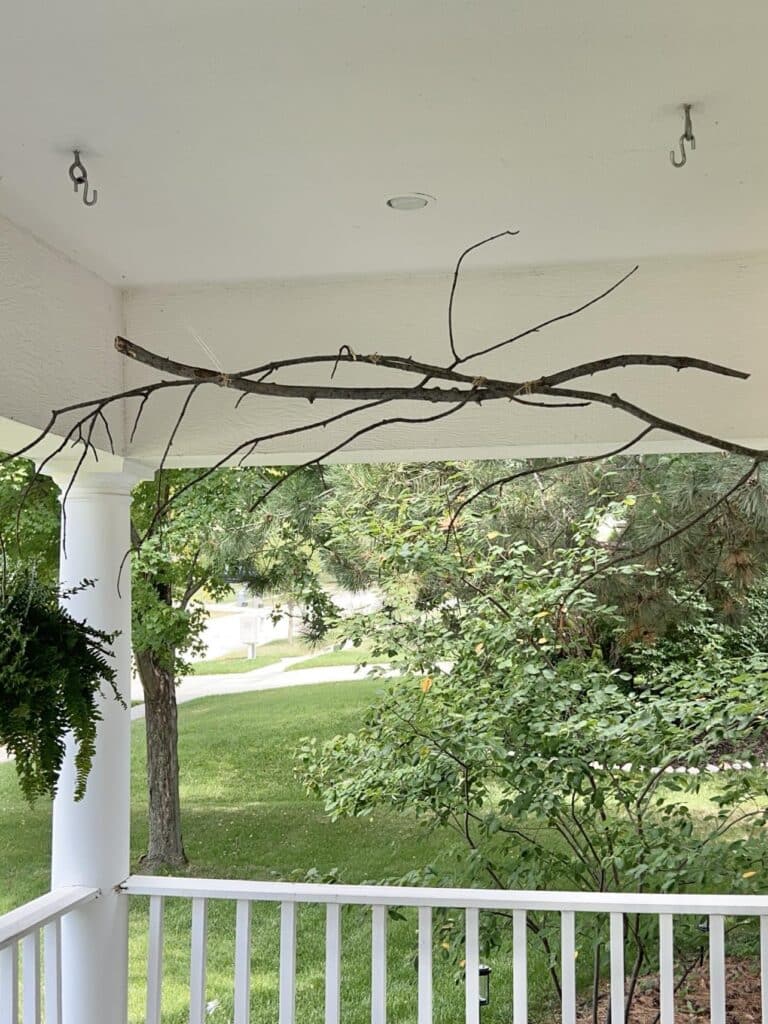 A hanging tree branch decor idea chandelier on a front porch.