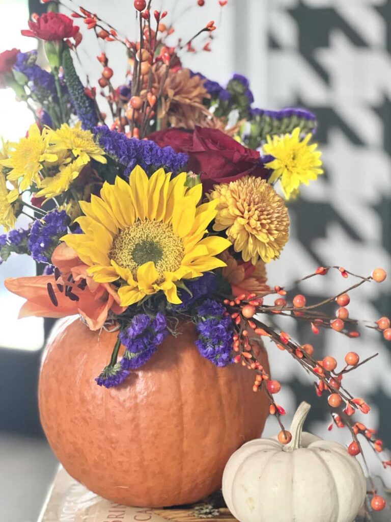 A pumpkin vase filled with flowers.