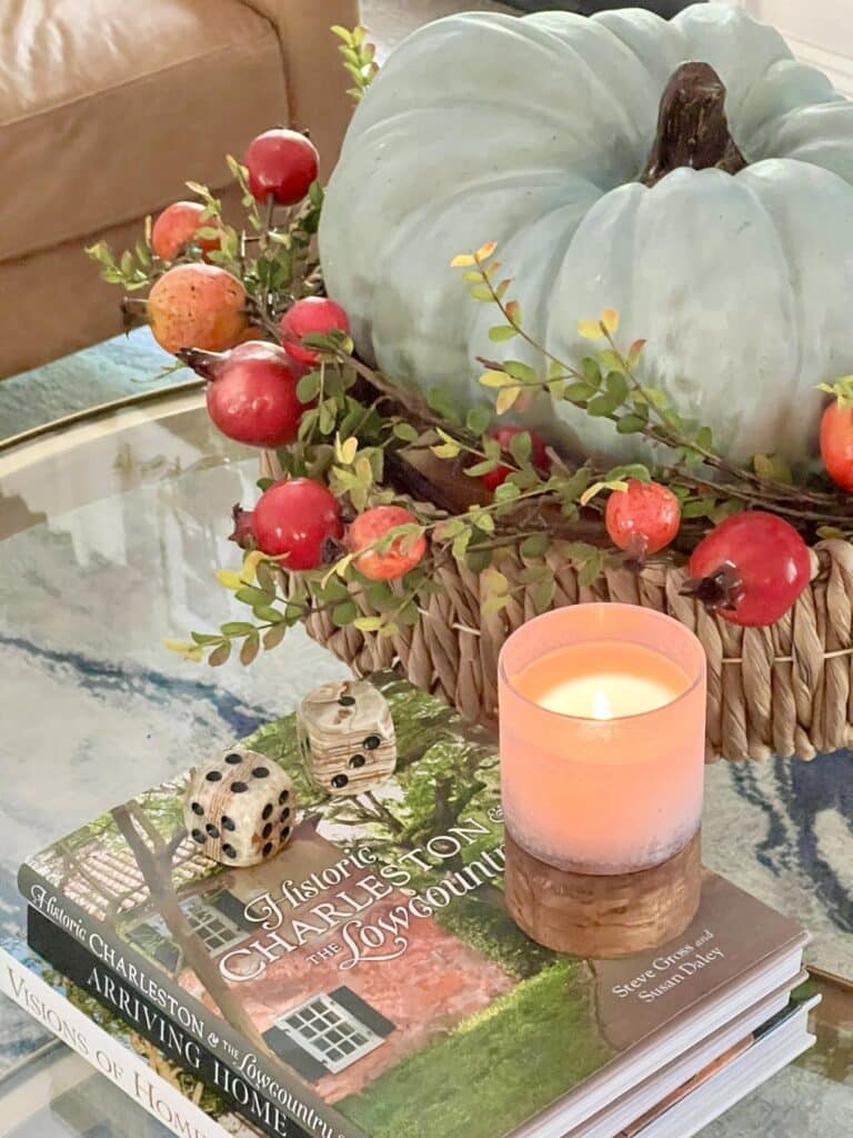 A large wood pumpkin and lighted candle are fall living room decorating ideas.