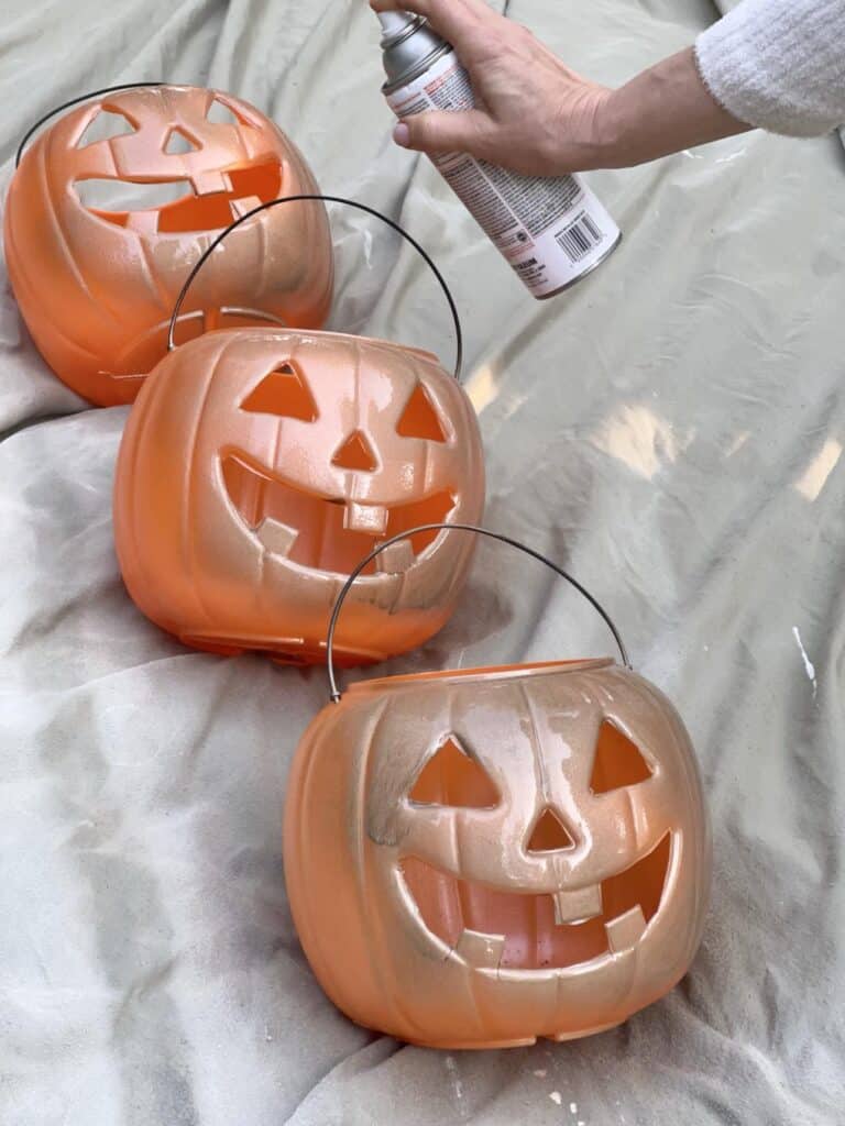 Spray painting pumpkin pails a gold color.