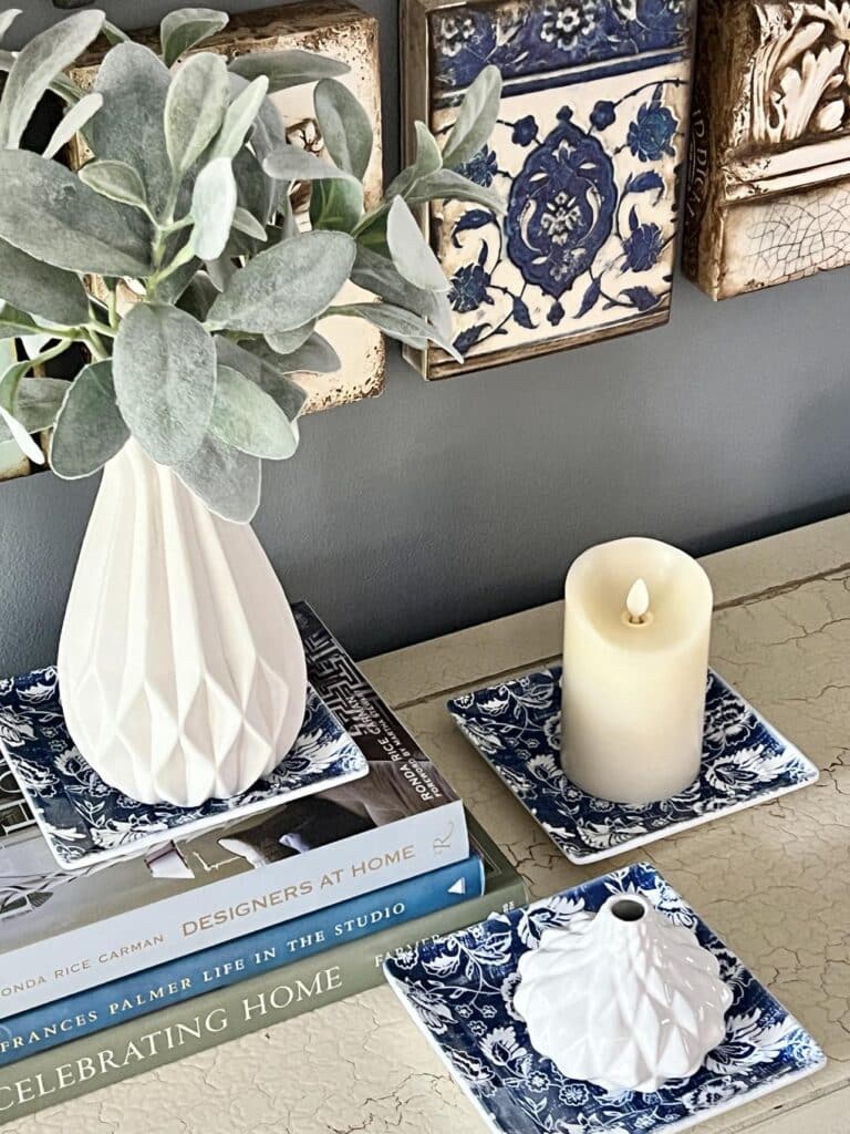 White vases and a candle sitting on top of blue and white snack trays.