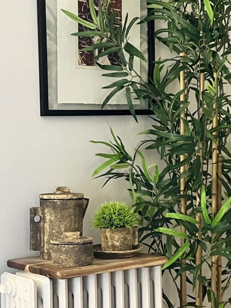 A radiator with a coffee set on top with a wood board in between.