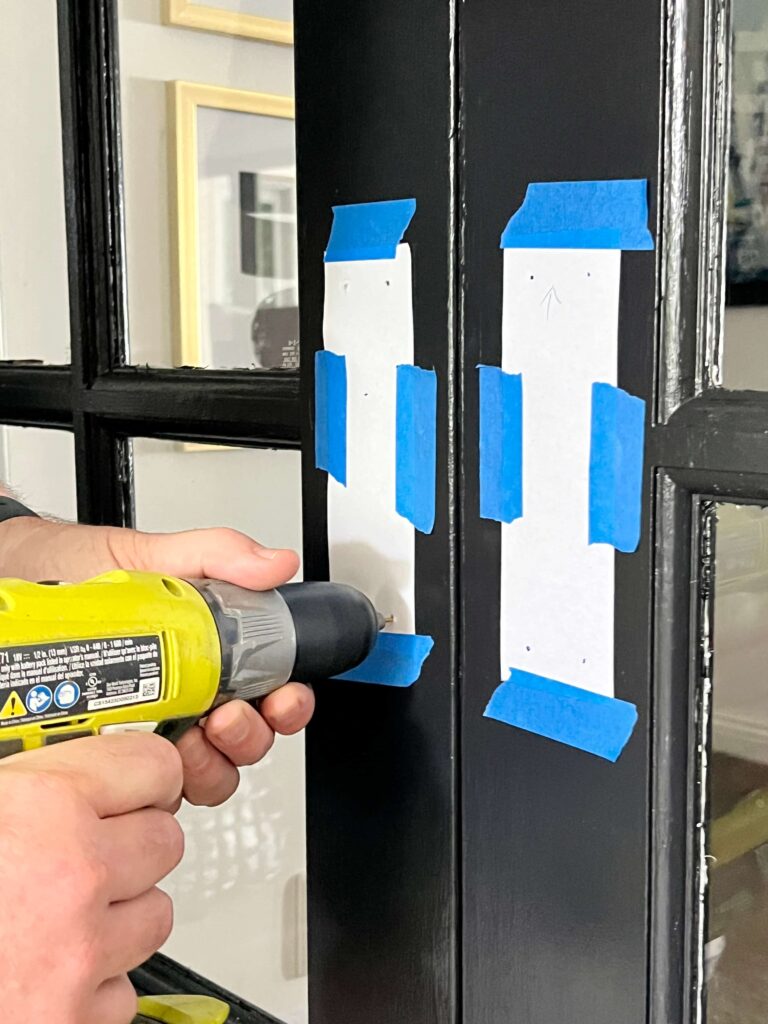 Drilling holes for door knobs on freshly painted French doors.