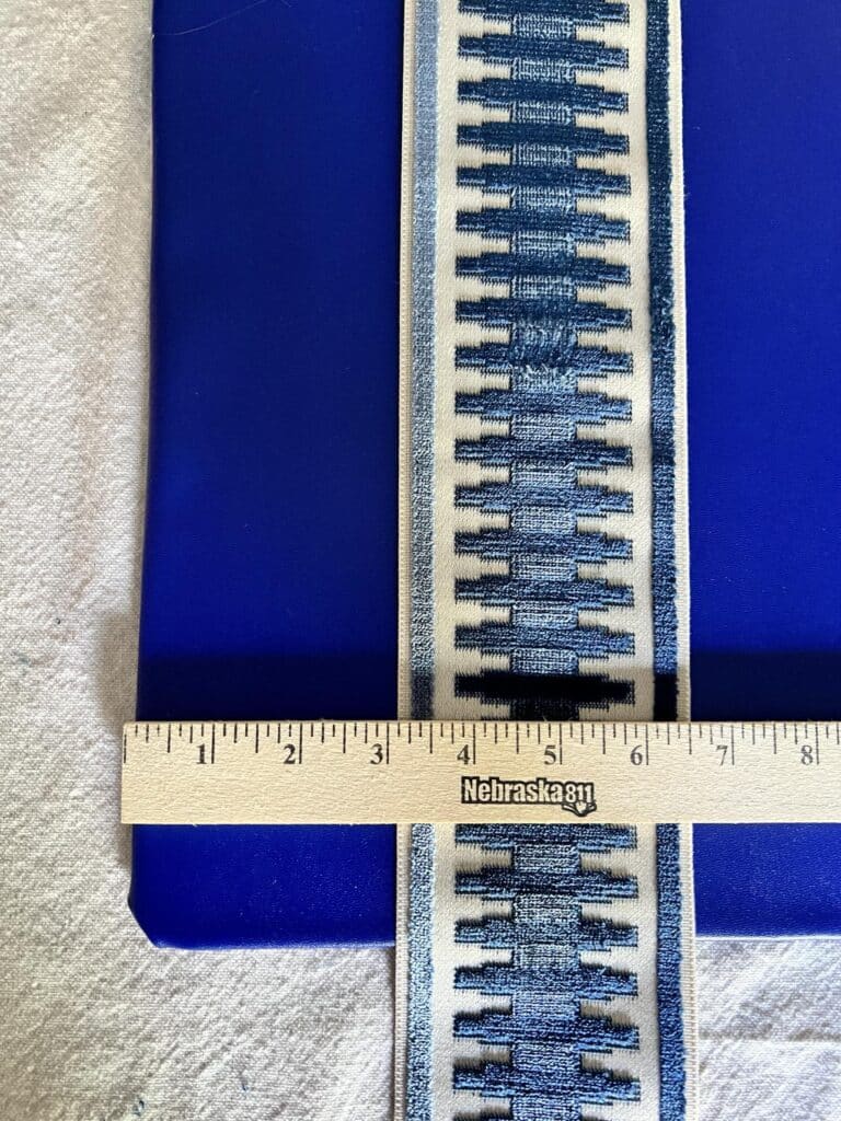 A diy desk pad with a strip of embroidered blue fabric trim tape and a yardstick.