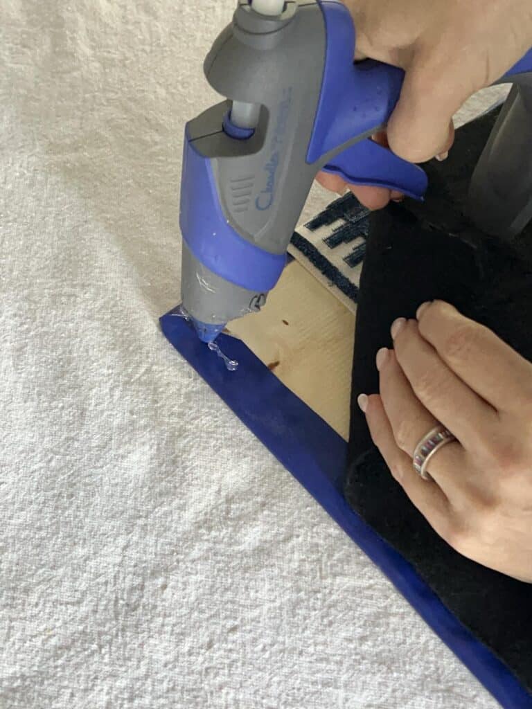 Gluing the corner of black felt to the corner of a diy desk pad.