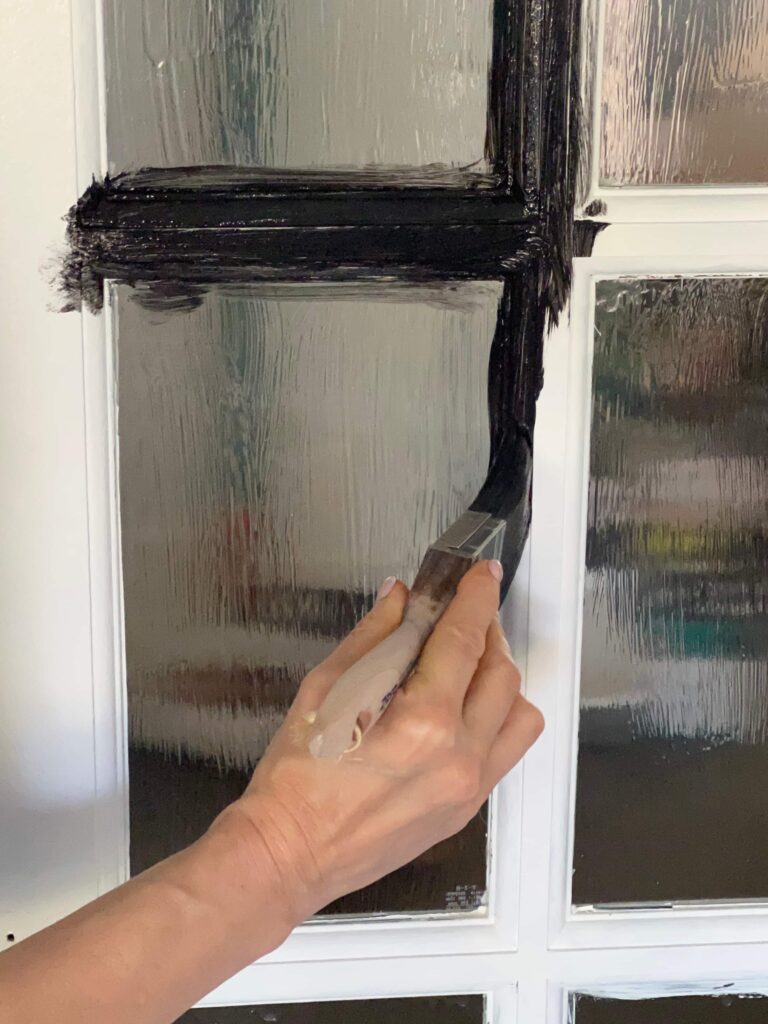 Using an angled brush for how to paint French doors with black paint.