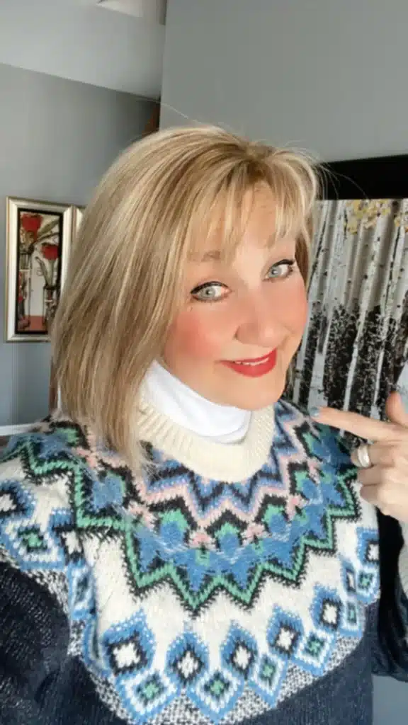 woman pointing to the turtleneck sweater she is wearing.