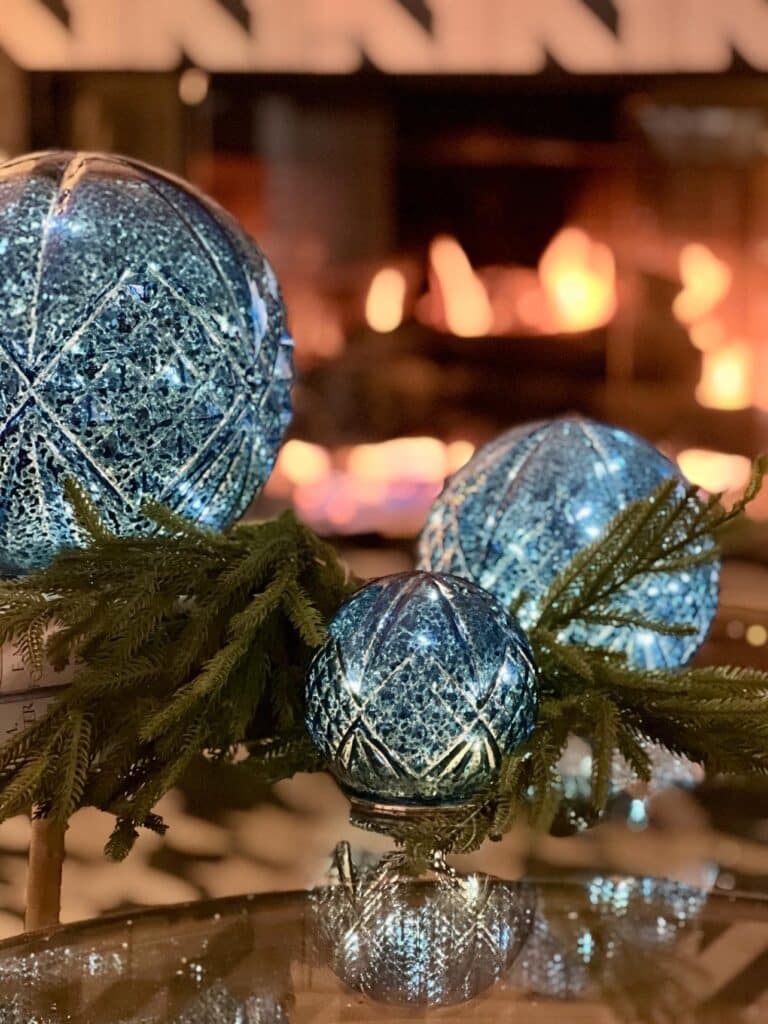 Glass spheres glowing blue in front of a fireplace.