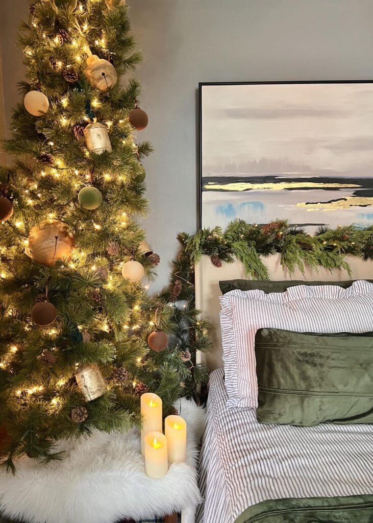 A Christmas tree beside a cozy bed.