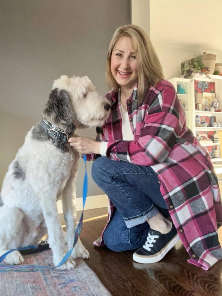 Woman wearing pink plaid shacket and black canvas sneaker crouched beside a white dog: How to wear sneakers