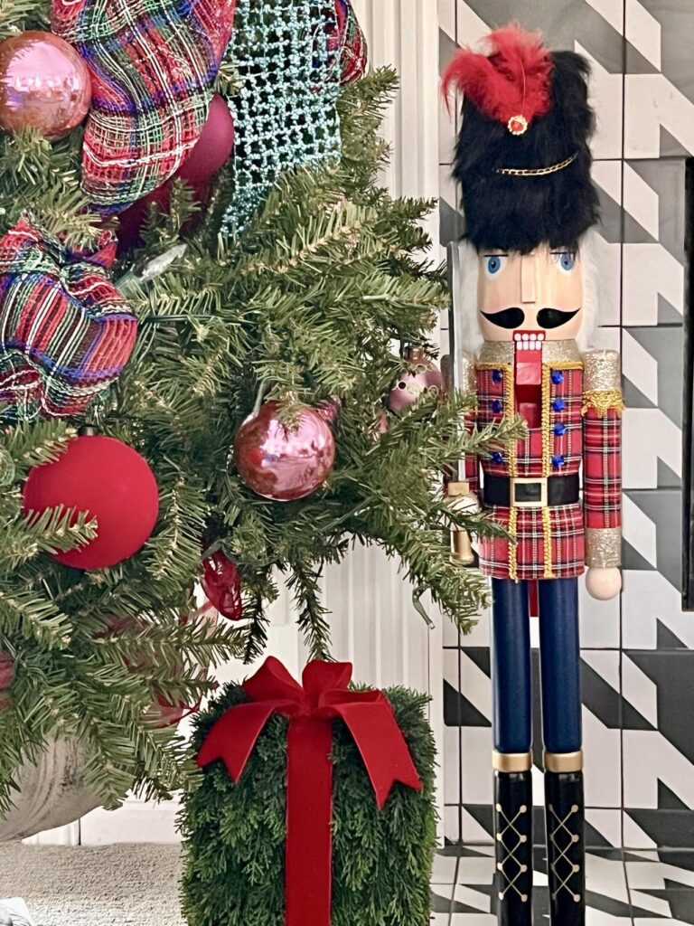 A nutcracker placed beside a Christmas tree as part of a home tour.