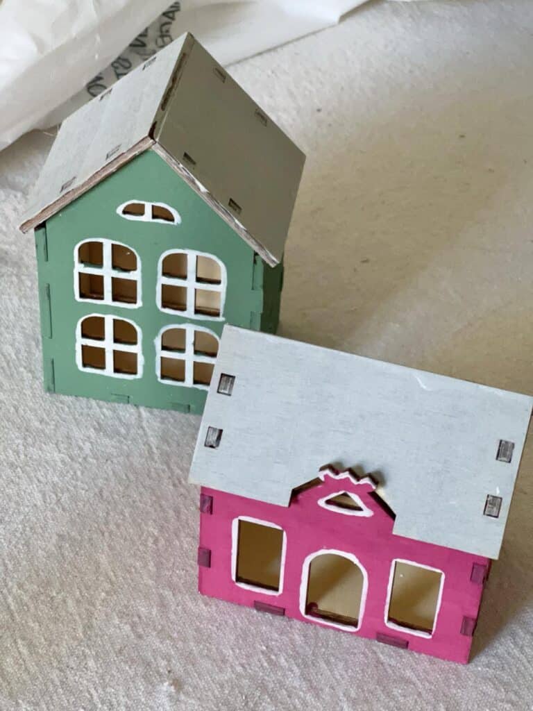 Two painted and outlined toy houses that will be glued into an Anthropologie DIY Christmas Wreath.