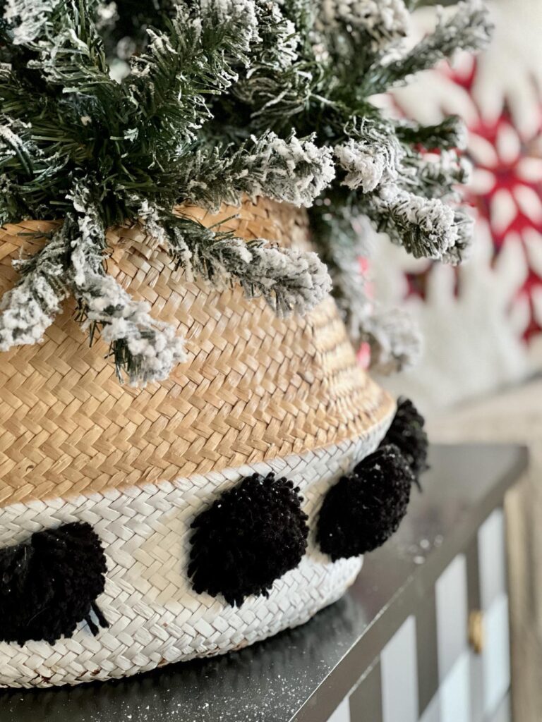 A pom pom basket used as a collar with a Christmas tree displayed inside.