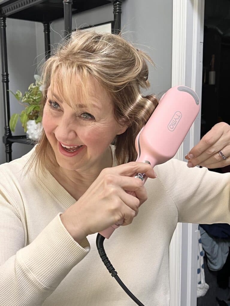 Woman clamping hair waver tool in a mid section of her hair: How to use a hair waver