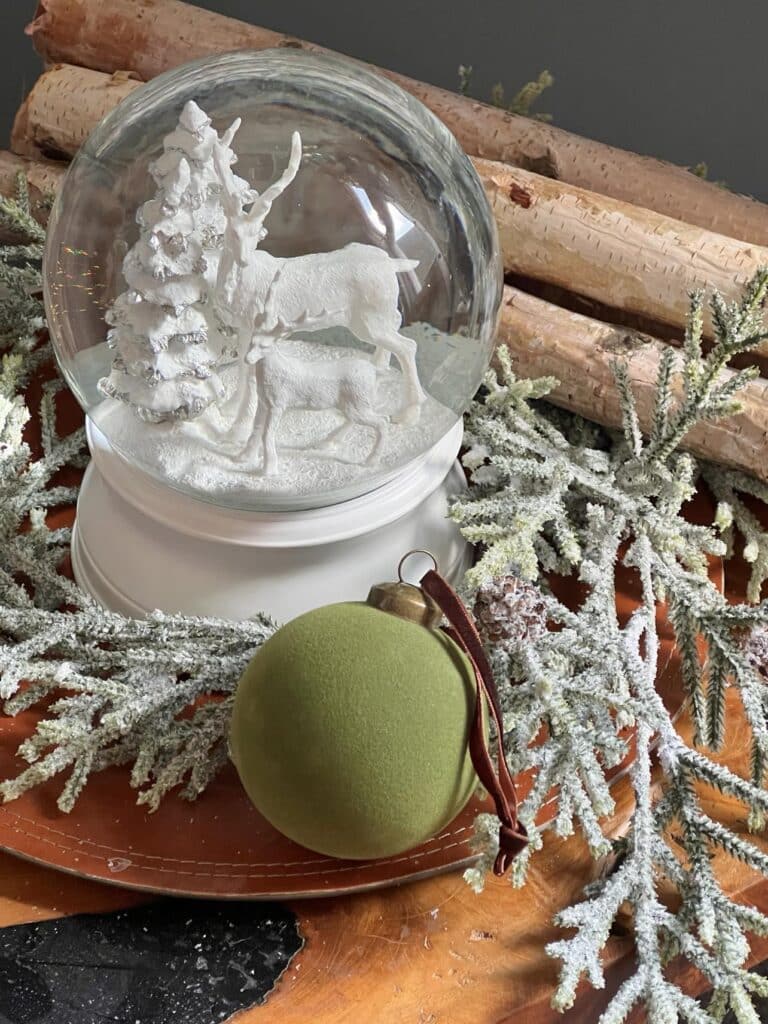 A reindeer snow globe nestled into faux greenery for Christmas.