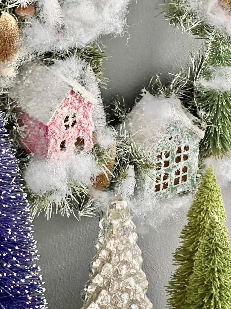 a pink and green snow glittered house in an Anthropologie DIY Christmas Wreath.