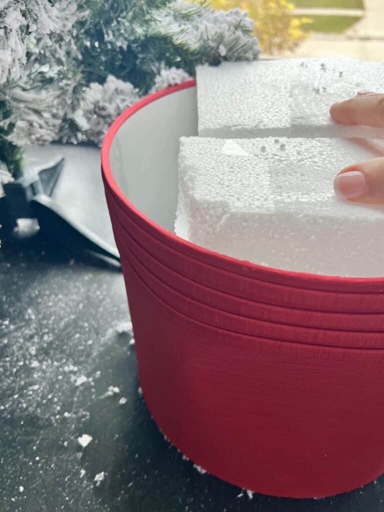 Stuffing styrofoam into a red lampshades for Christmas tree collar ideas.