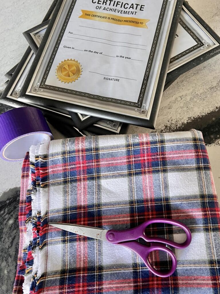 A stack of certificate frames and plaid fabric.