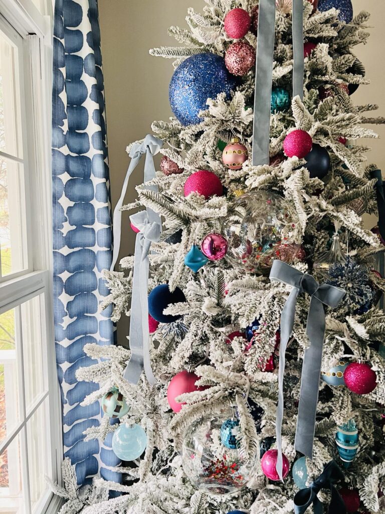 A flocked Christmas tree decorated with bows for a home tour.