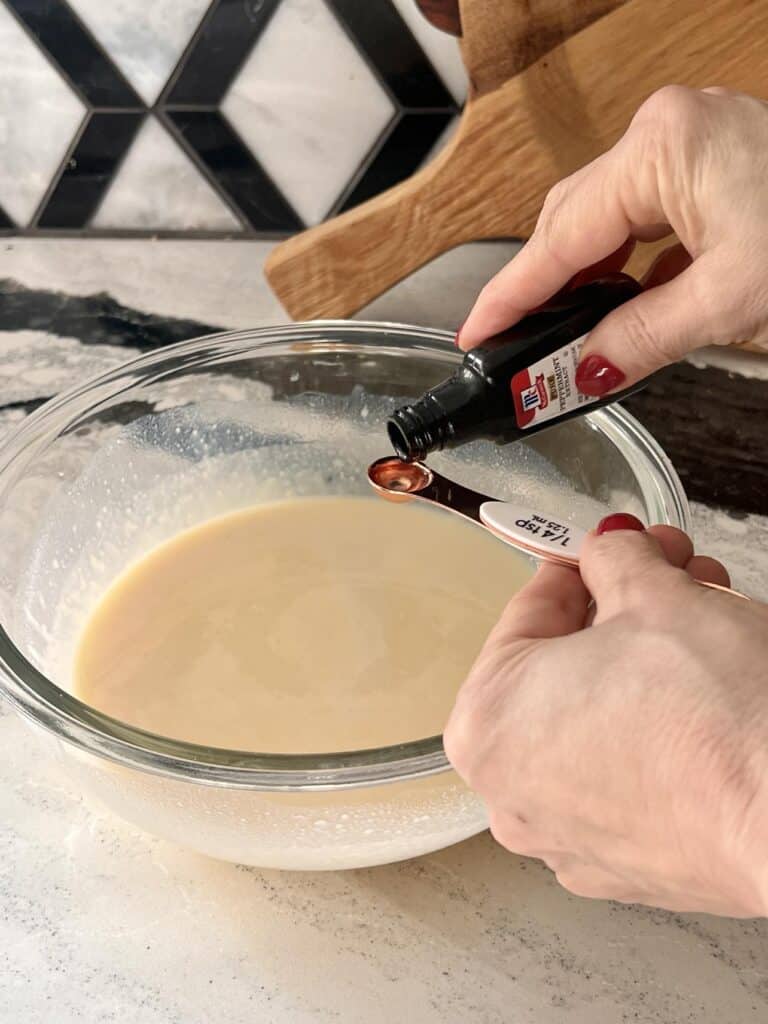 Adding peppermint extract to RumChata cheesecake pudding shots mixture.