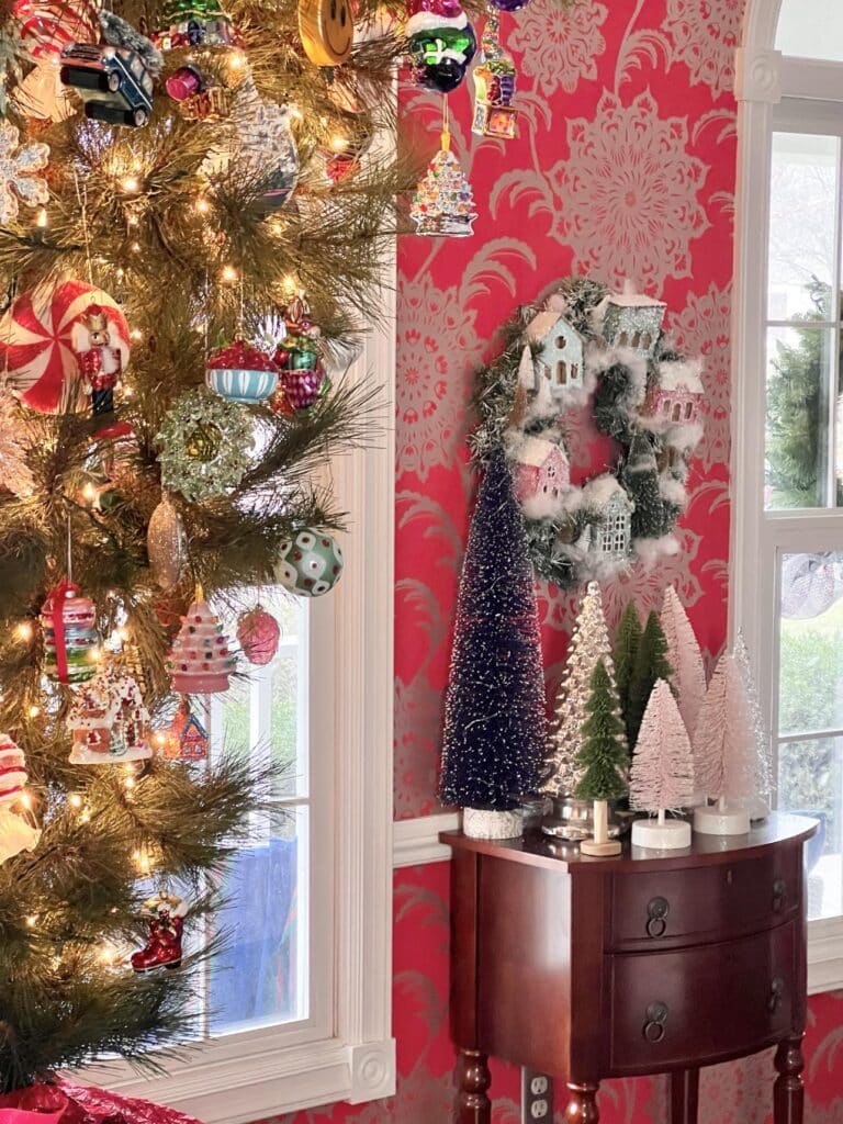 An alpine wreath hanging against red wallpaper in a Christmas dining room.