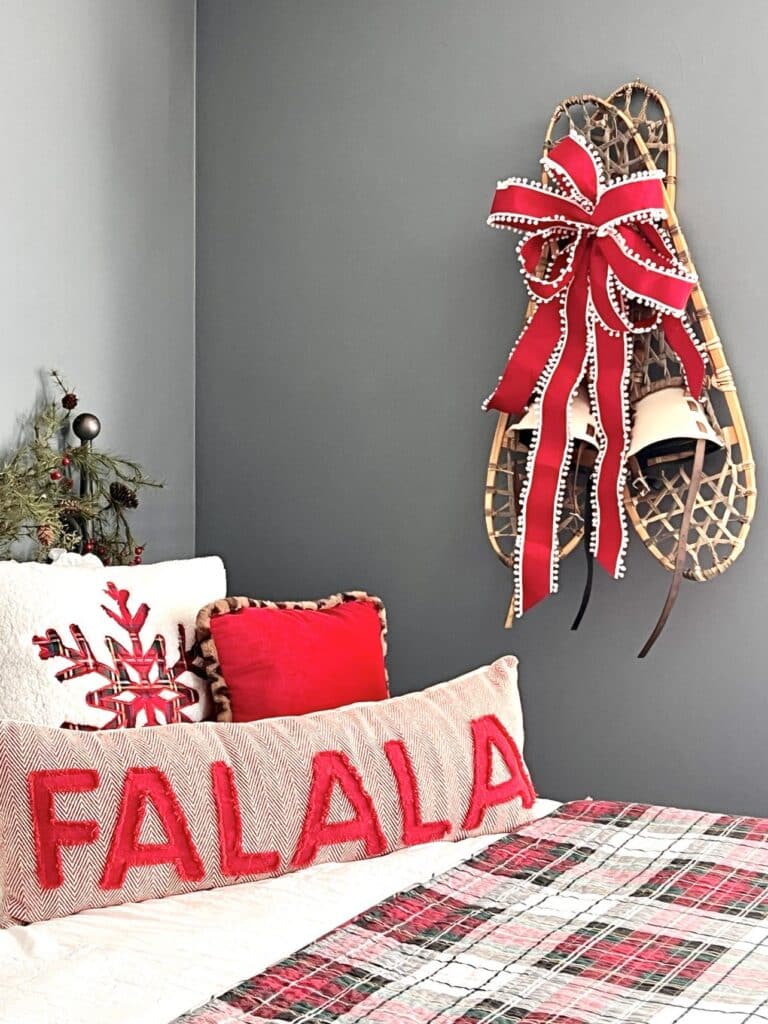 Decorating with snowshoes by attaching a red bow to the center of the shoes.