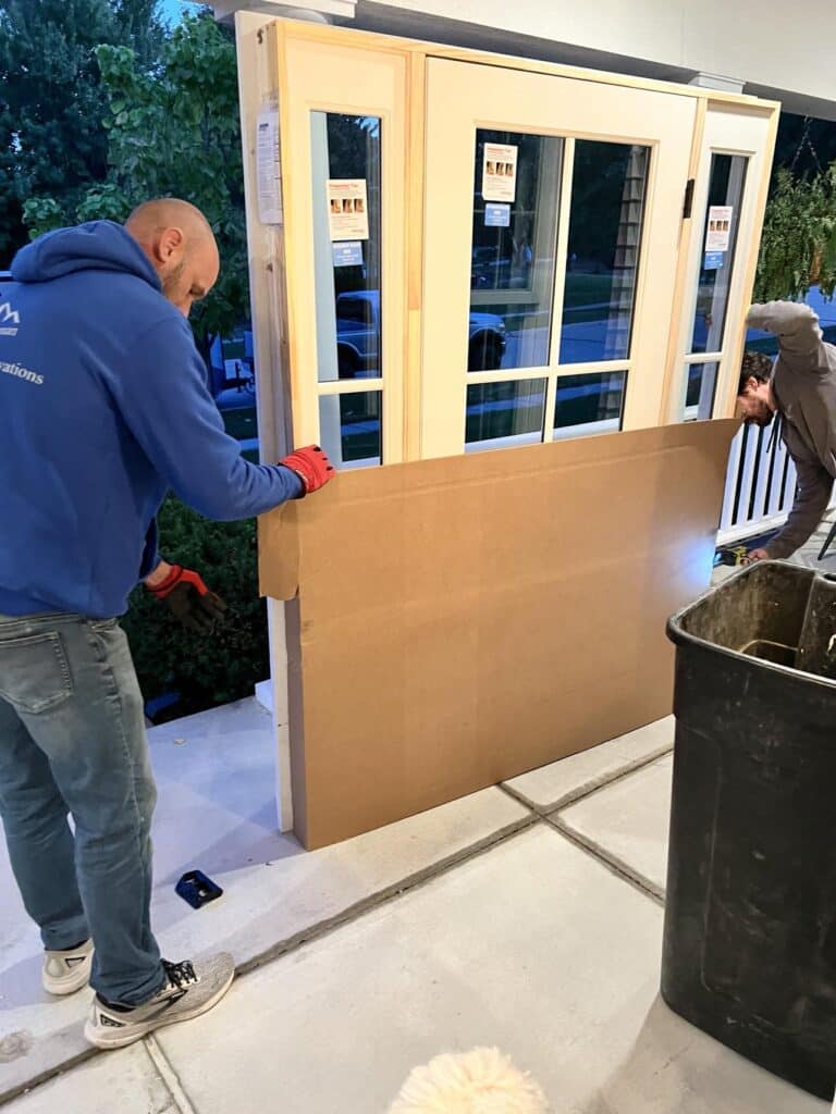 Two men unboxing a new door for front porch ideas.