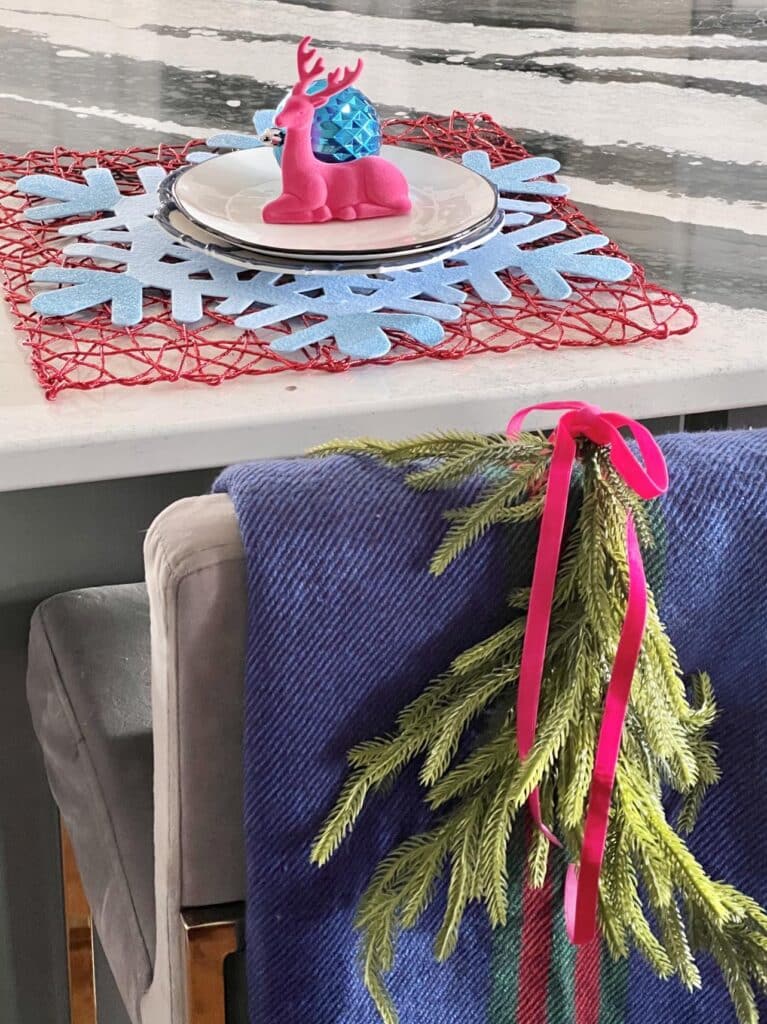 A plaid scarf thrown over a bar stool with greenery on top.