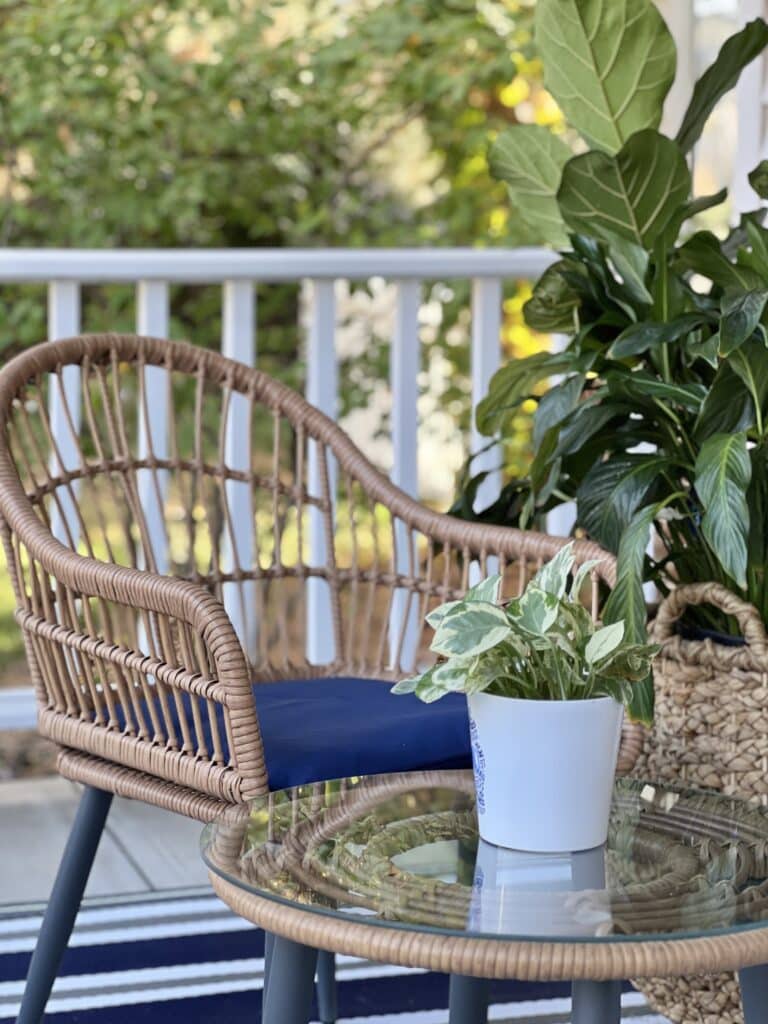 Front porch ideas include a wicker chair with a small coffee table holding a green plant.