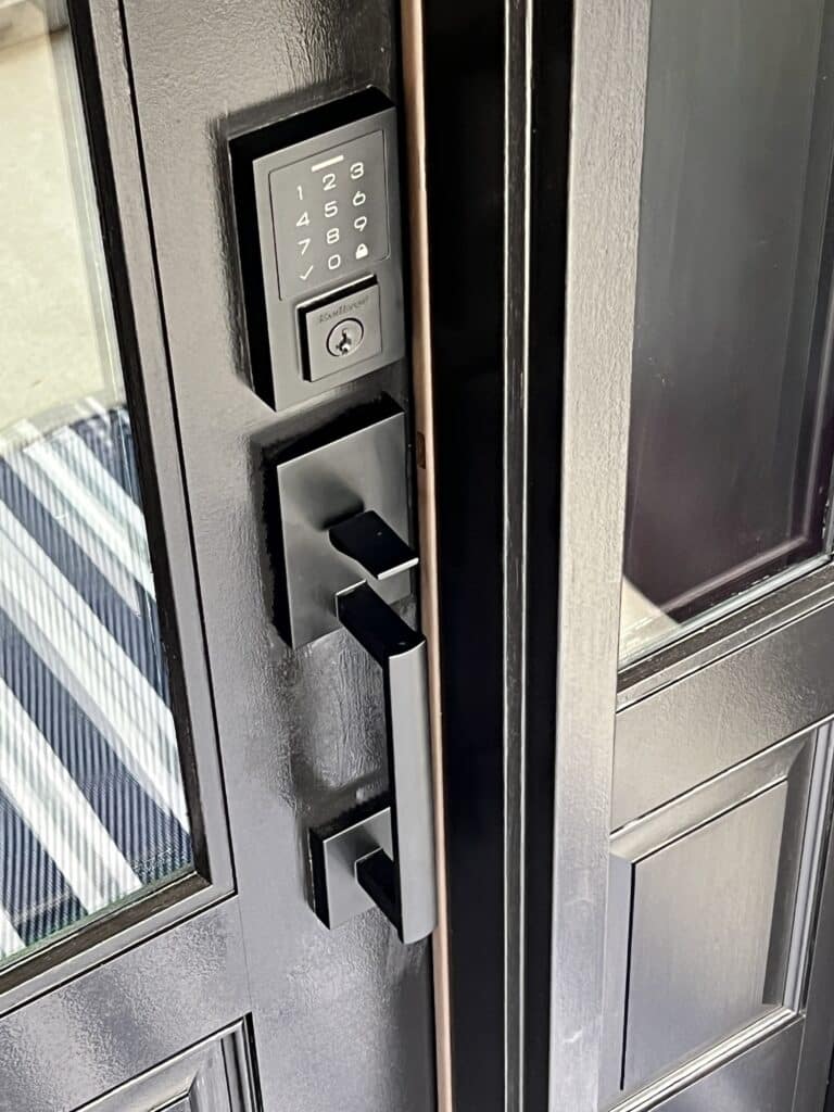 A front porch door with a black door handle and keyless entry lock.