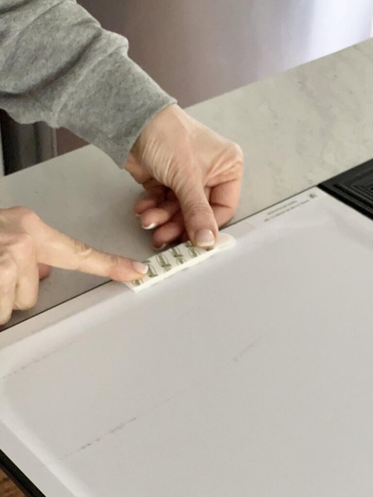 Applying velcro Command strips to the back of a mirror.