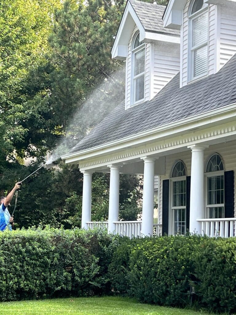 A man power washing the exterior of a front porch.