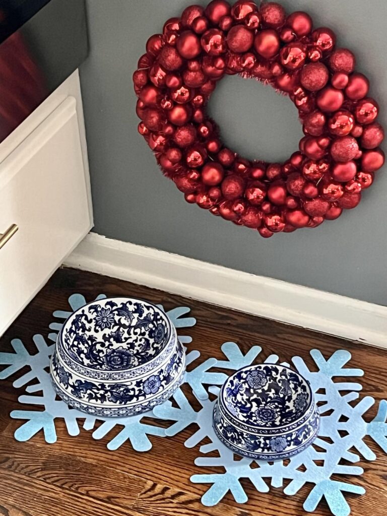 A red ornament wreath hung over blue and white dog dishes.