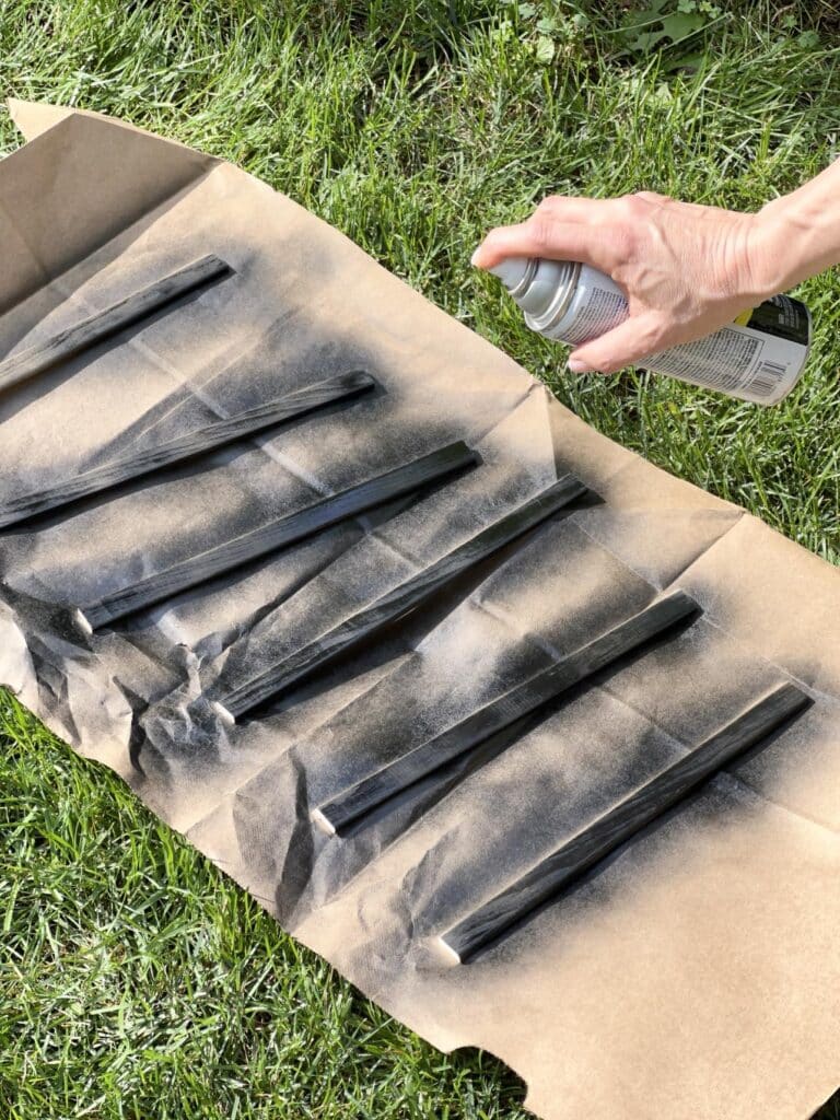 Spray painting wood molding pieces with black spray paint.