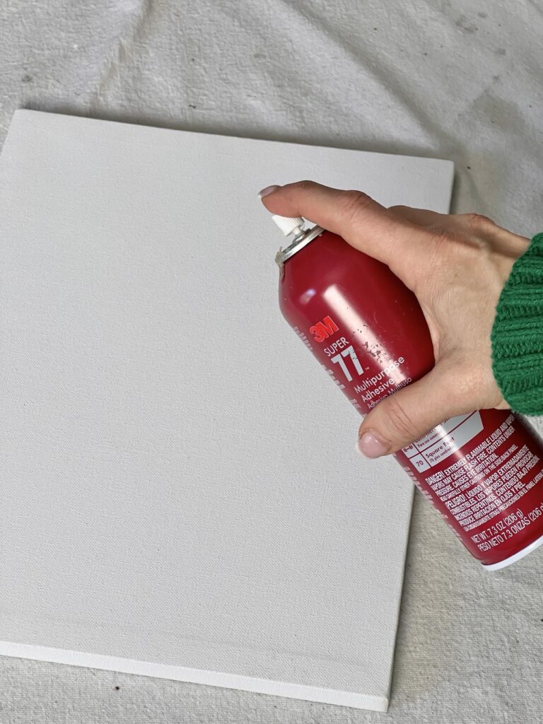 Spraying adhesive on a blank framed canvas.