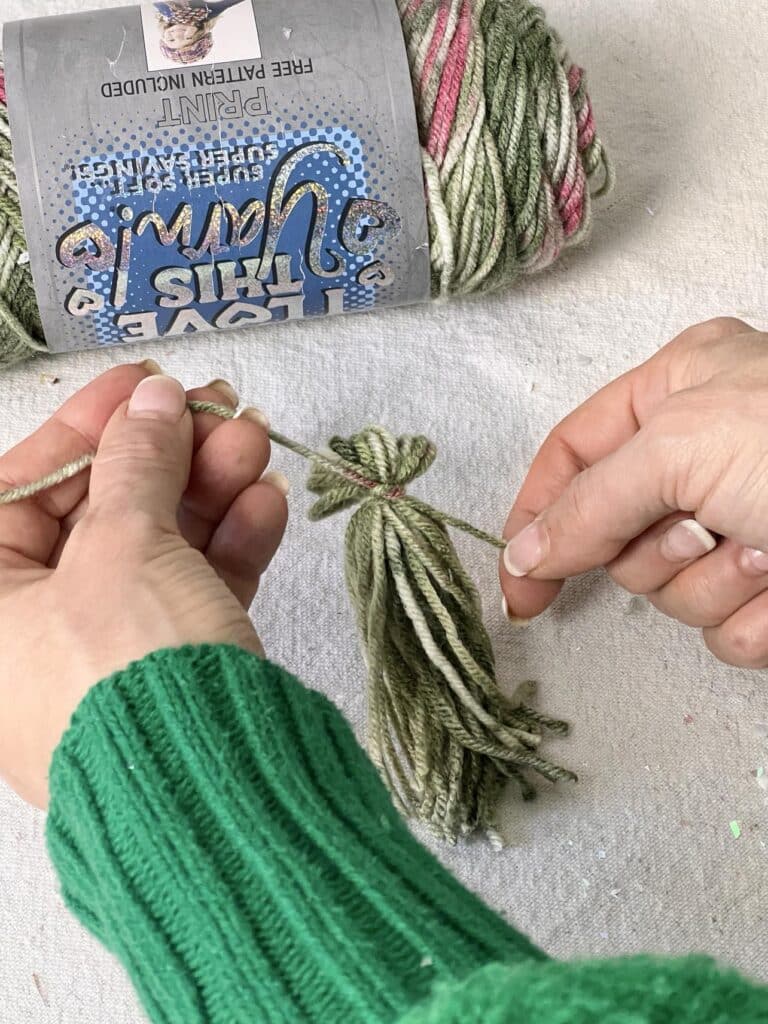 Tying a knot around the top of a Christmas tree tassel.