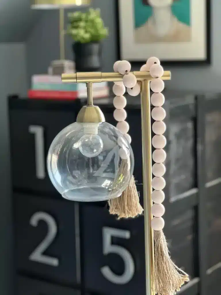 A desk lamp in the bedroom wrapped with a bead garland.