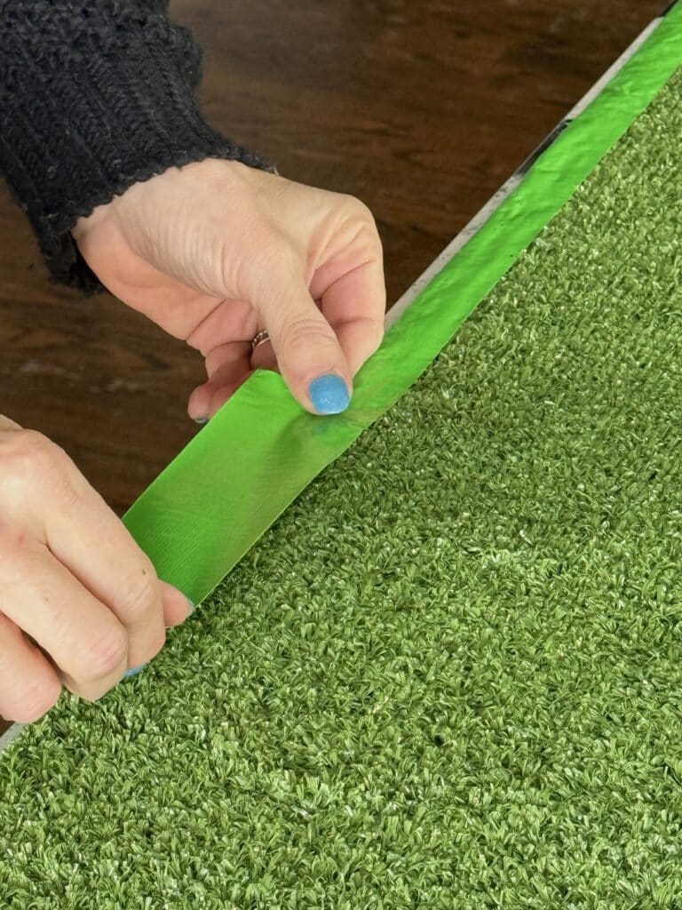 Wrapping the edge of artificial turf with green duct tape.