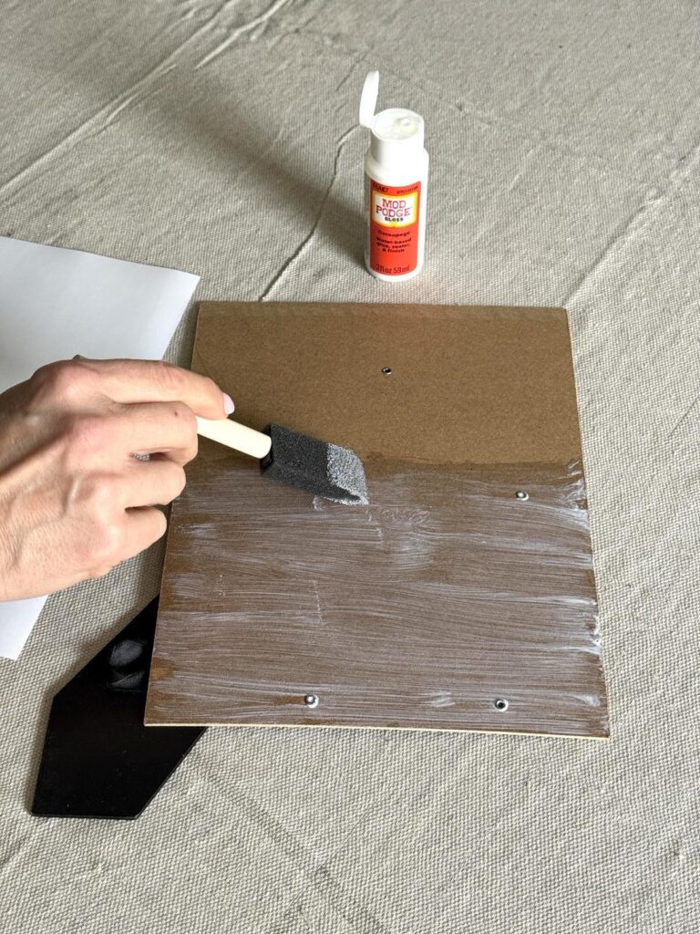 Brushing ModPodge across the back of a photo frame.