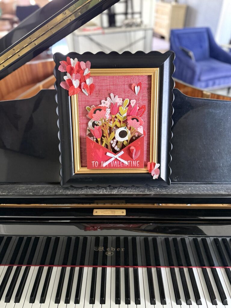 Valentine art displayed on a black piano.