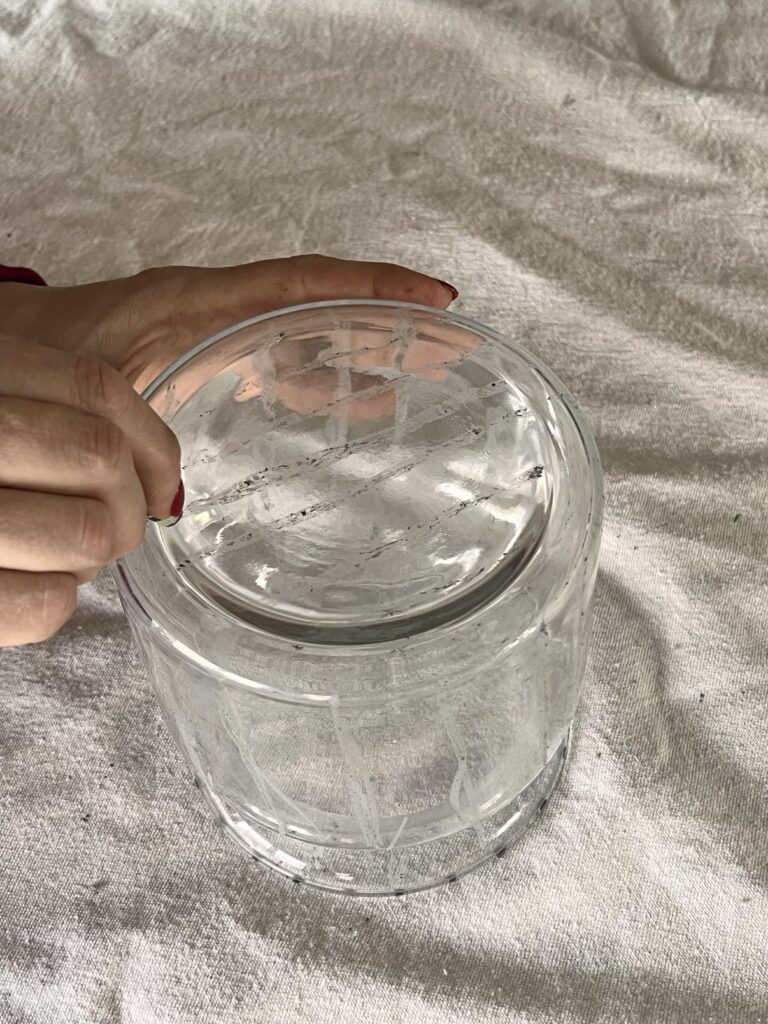 Drawing crackle glass lines onto the bottom of a vase with a grey crayon.