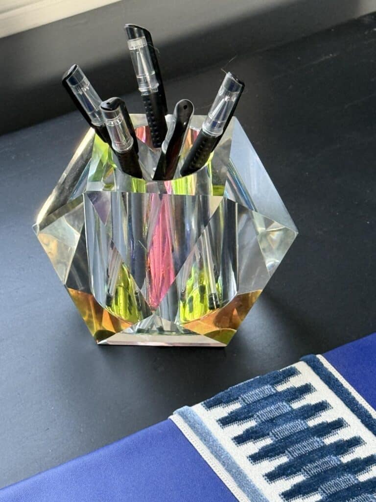 A glass votive holding pens for how to decorate a desk in a bedroom.